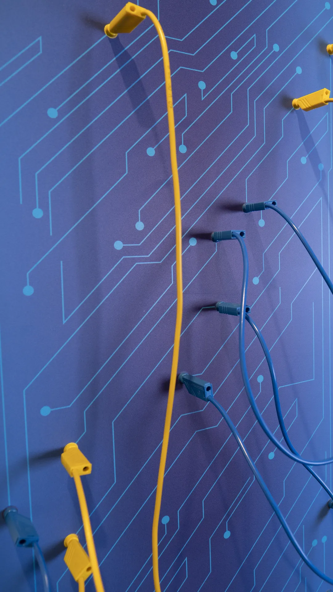 Kommunikationskonzept für Showroom für ABUS-Kransysteme mit interaktiver Wand mit gelben und blauen Kabeln auf Schaltplan-Grafik im VITAL-Raum von Abus
