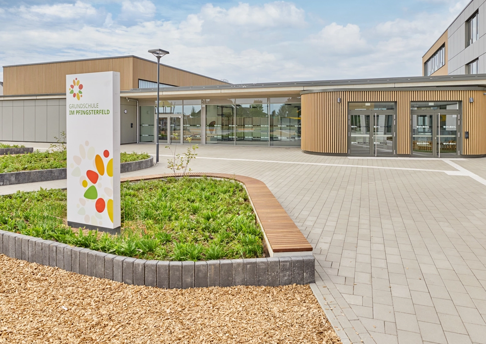 Exterior shot of the entrance area of the Waldschlösschen Comprehensive School in Velbert, with the guidance system column in the foreground and the school building in the background. Realized in collaboration with Goldbeck West and the R211 agency.