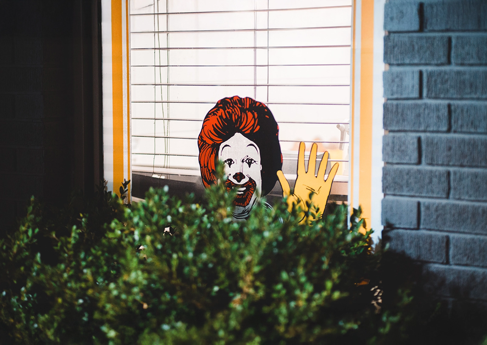 Image of the figure Ronald McDonald, partially obscured behind a green bush – as a symbolic representation of how strongly brand images remain recognizable even in fragmented form. Context: Branding.