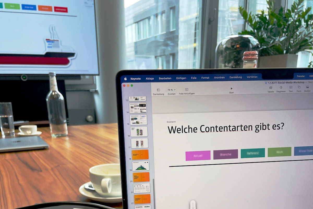 Shot from a social media workshop in the conference room: In the background, a monitor with cropped content on the topic, in the foreground, a conference table. Execution and conception by the R211 agency.