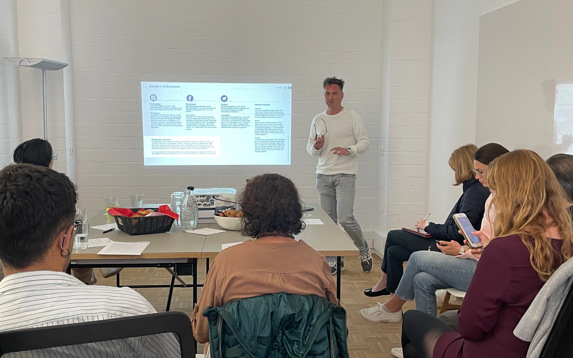 Shot from an R211 workshop on Marketing, B2B, and Social Media: A group of participants follows the presentation of an R211 employee, who explains content in front of a screen.