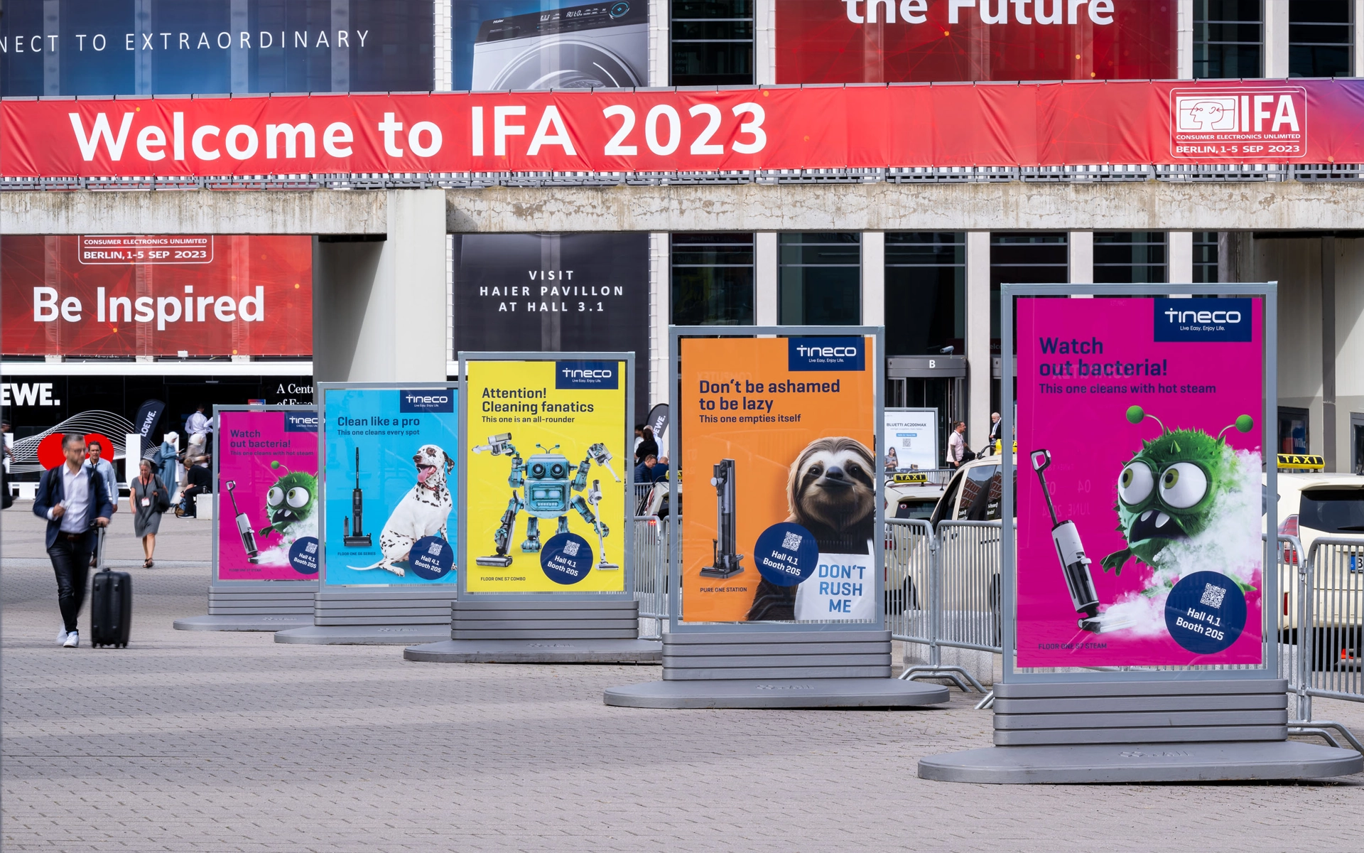 Außenansicht des IFA-Messegeländes mit dem Haupteingang, flankiert von fünf großformatigen Werbeplakaten für das Unternehmen Tineco. Die Plakate, gestaltet von der Agentur R211, bewerben den Messeauftritt von Tineco auf der IFA.
