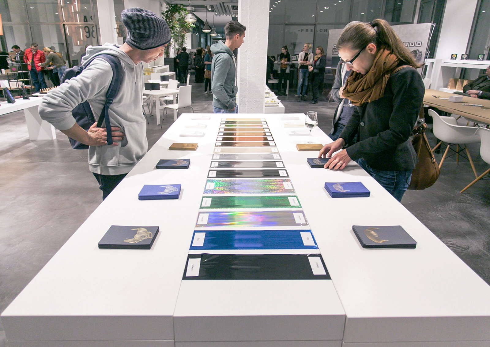 Eventbesucher, die das präsentierte Papier anschauen. Aufnahme vom Paper Playground Event von Freytag & Petersen, visuell gestaltet von der R211-Agentur.