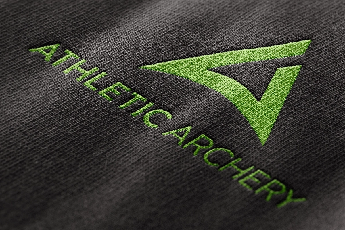 Image of the Athletic Archery logo as an embroidered version on a shirt – as an example of brand-compliant application on textiles.