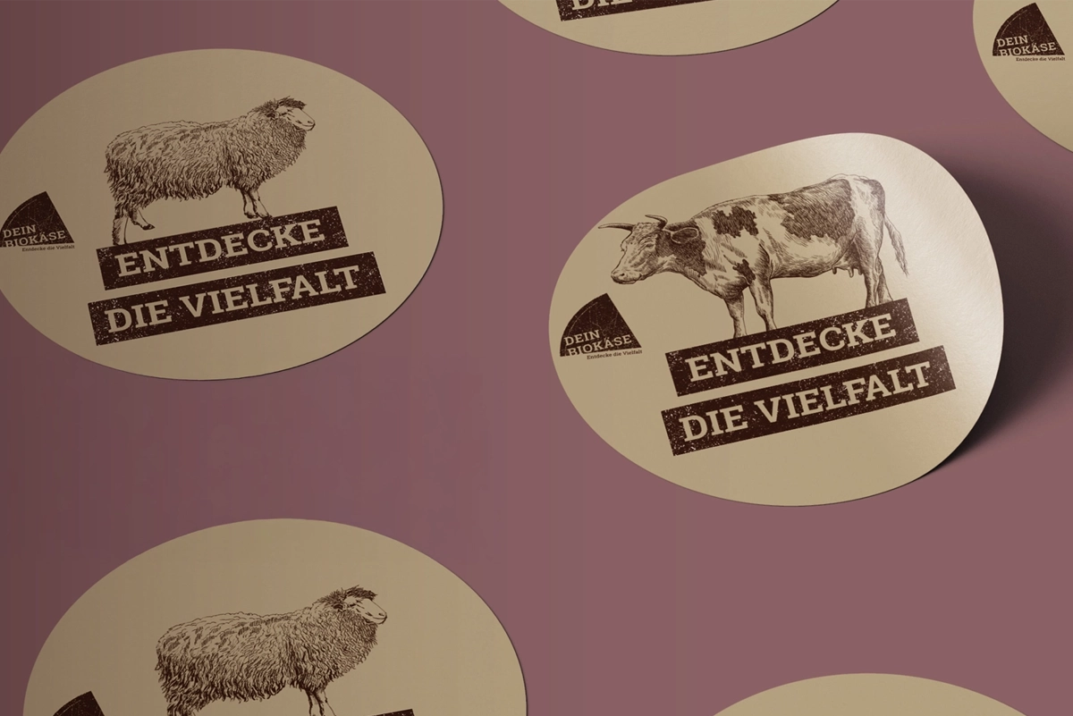 Round stickers from DEIN BIOKÄSE with golden accents and logo – designed as a Branding element.