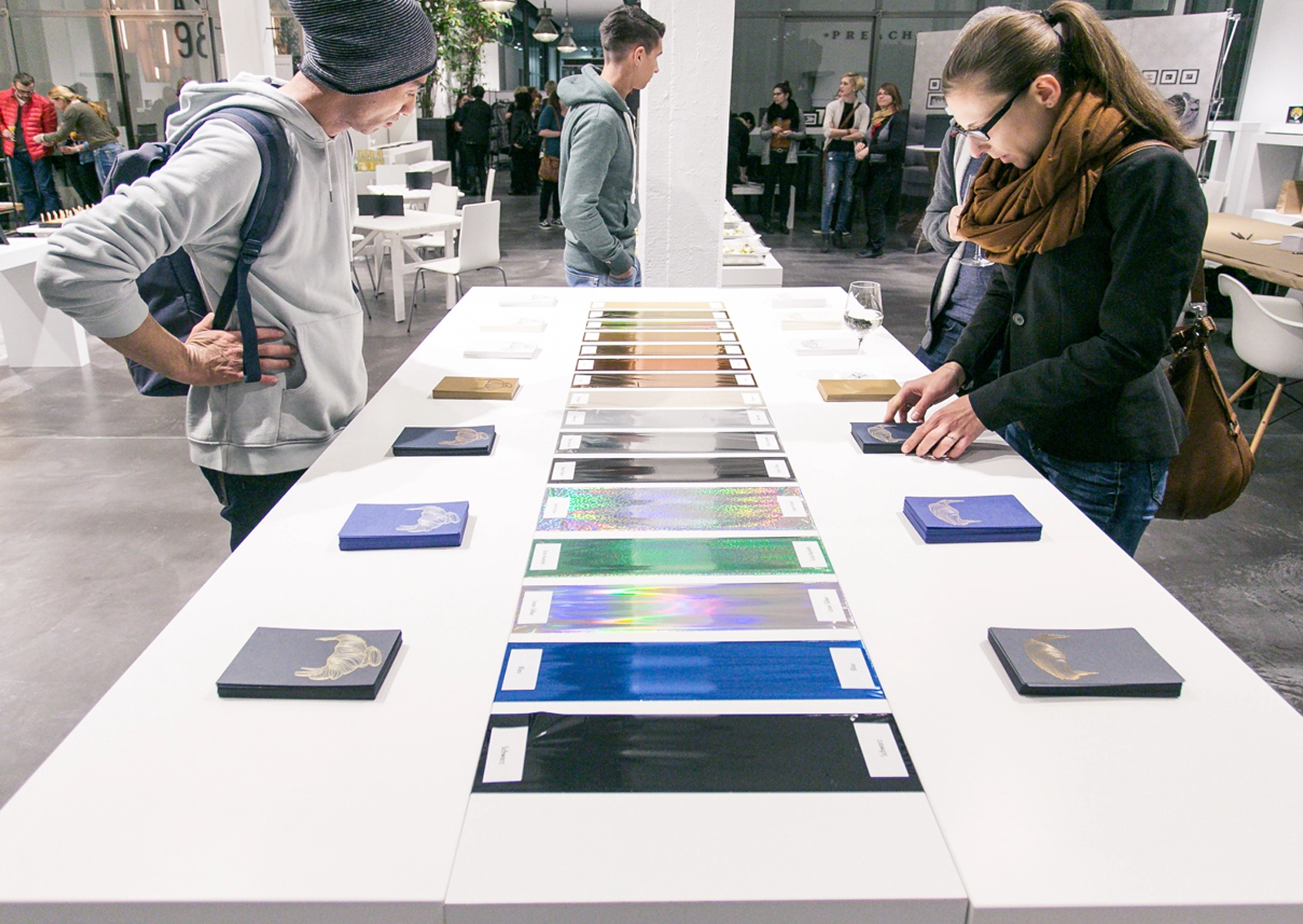 Eventbesucher, die das präsentierte Papier anschauen. Aufnahme vom Paper Playground Event von Freytag & Petersen, visuell gestaltet von der R211-Agentur.